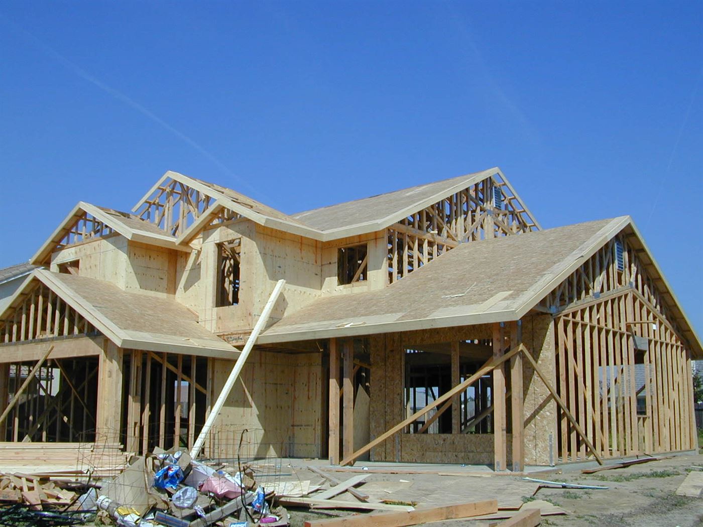 A timber-framed house under construction, with roof trusses and wall studs exposed